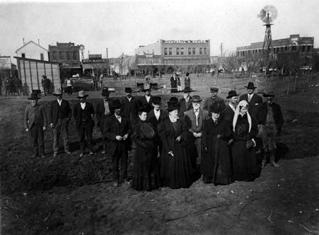 The white frame building in the left top corner was the Courthouse built in 1890. Front row left to right: C. C. Poff, Mrs. T. A. Gray, W. G. Conner, Mrs. W. G. Conner, Judge J. T. Hall, Mrs. J. L. Stallings, Mrs. Annie Turney Haile Back row left to right: Fred Scott, Mr. Goodman, Bob Bishop, Will Jowell, Martin Fehr, Enoch Jackson, W. B. Hutchinson, J. L. Stallings, J. L. Cantrell, T. W. Tomlinson, T. A. Gray In the background: Mrs. George Tomlinson and Mrs. T. W. Tomlinson grndbrkg.jpg